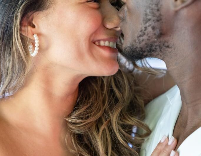 Close-up of a joyful couple about to kiss, showcasing a beautiful engagement ring