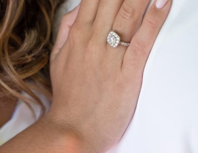 A close-up view of an elegant engagement ring with a sparkling diamond on a woman's finger